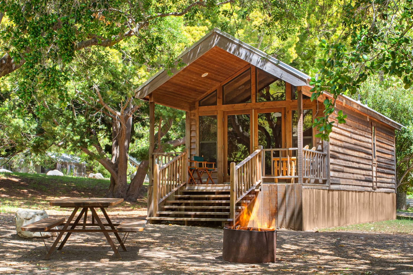 A cedar cabin with a porch and picnic table beneath trees at El Capitan Canyon.